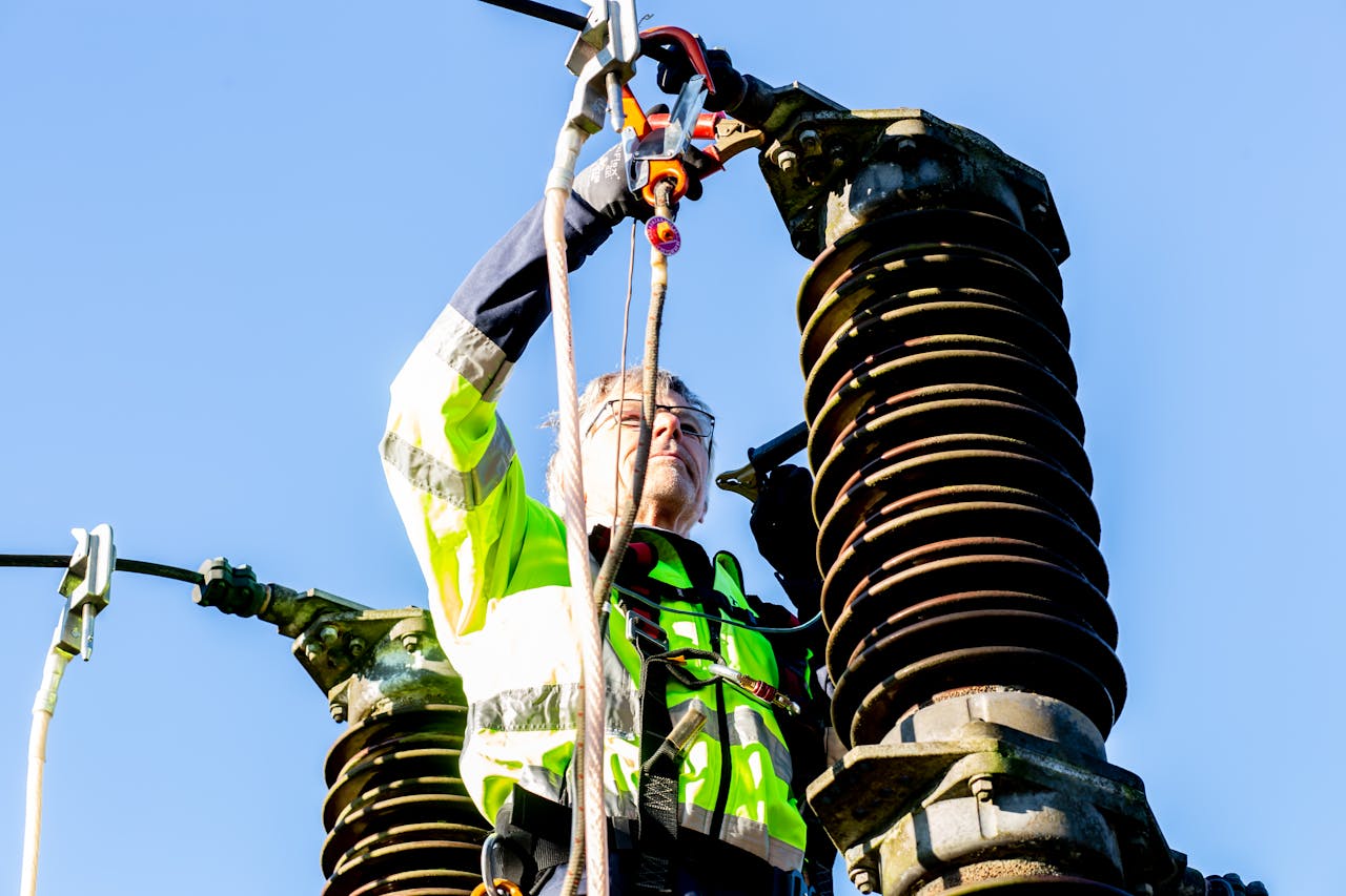 services-03 Safety-conscious worker inspecting high-voltage power structures on a clear day.