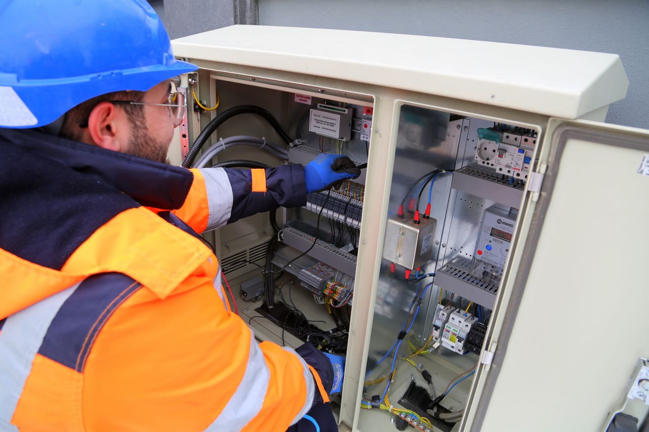 services-02 Engineer in safety gear working on an outdoor electrical panel, ensuring system functionality.